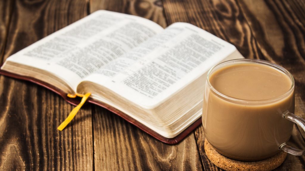 раскрытая библия и чашка кофе